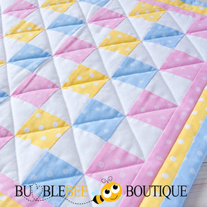Close-up of Baby Dots pink, blue & yellow mini patchwork quilt front